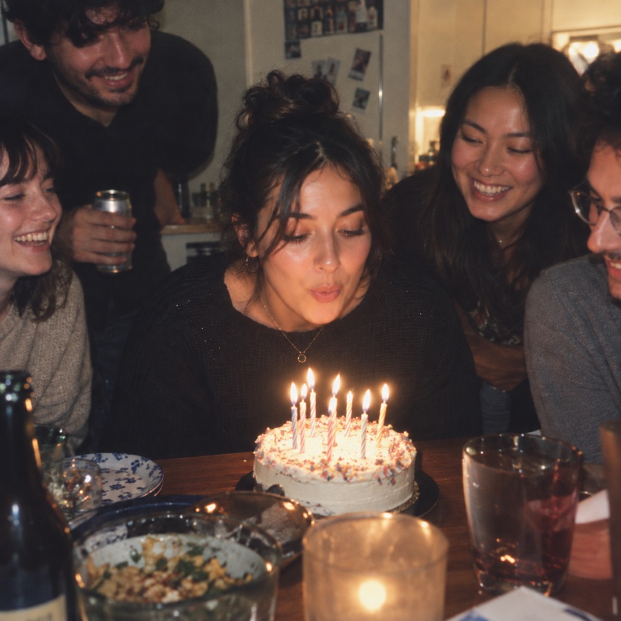 A birthday wish by candlelight, surrounded by friends