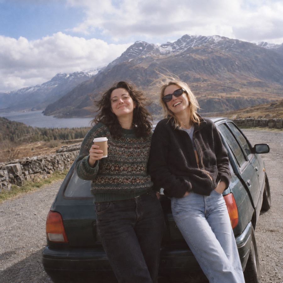 Two loved ones smiling together on a mountain road trip